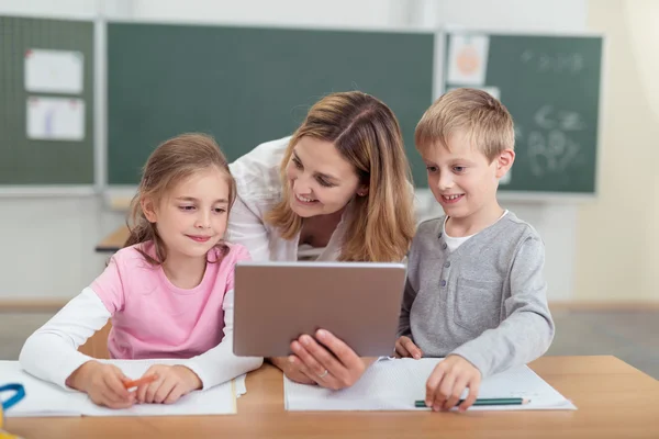 Läraren visar en tablett till två unga studenter — Stockfoto