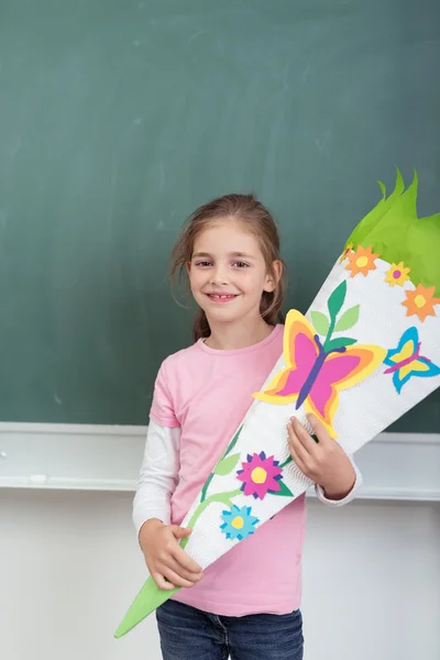 Mooi meisje Holding haar Artwork tegen schoolbord — Stockfoto