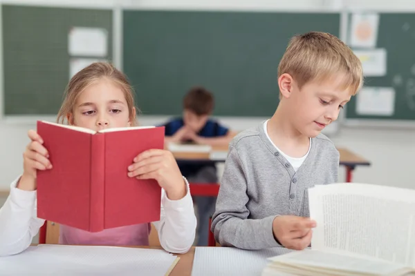 Two young school pupils reading from textbooks — Stock Photo, Image