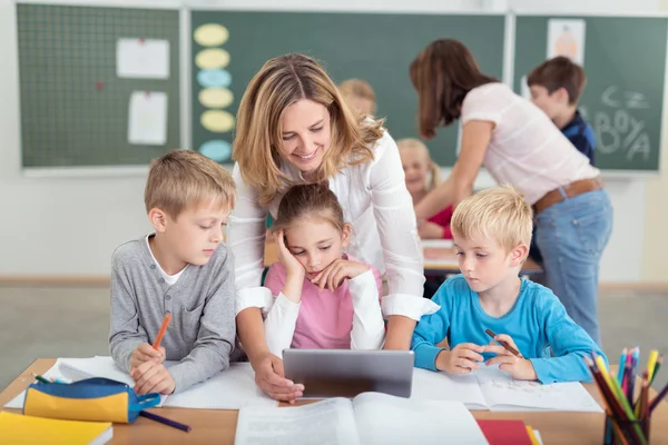 Maestra y niños mirando juntos la pantalla de la tableta —  Fotos de Stock