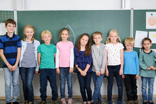 Kids Standing Against Chalkboard in Classroom — Stock Photo, Image