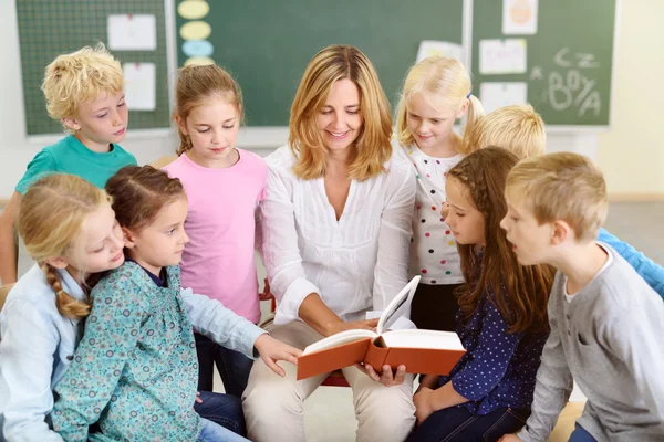 Maestra leyendo un cuento a niños dentro del aula —  Fotos de Stock