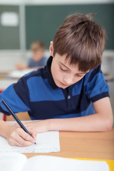 Young schoolboy sitting working at his desk — Stock Photo, Image