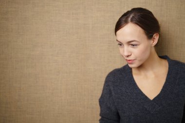 Thoughtful Girl Against Brown Wall clipart