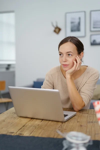 Mulher atenciosa com laptop olhando para longe — Fotografia de Stock