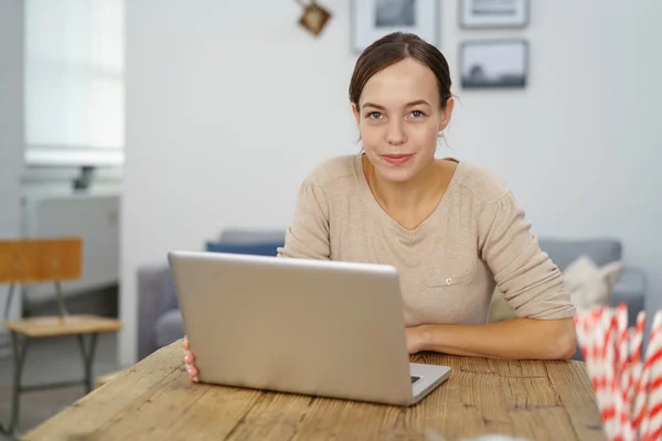 Femme souriante assise à son bureau avec ordinateur portable — Photo