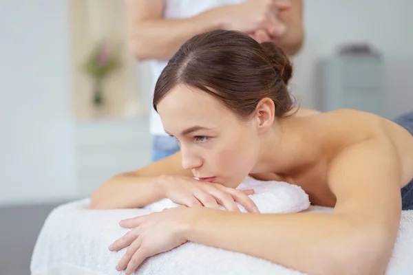 Mulher Pensiva deitada na cama pronta para massagem — Fotografia de Stock