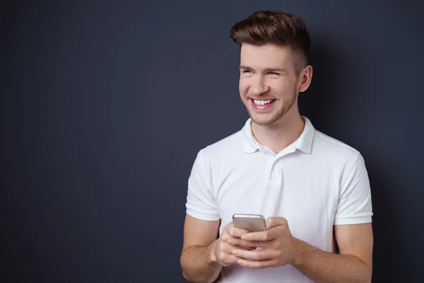 Hombre riendo y sosteniendo su teléfono inteligente en sus manos —  Fotos de Stock