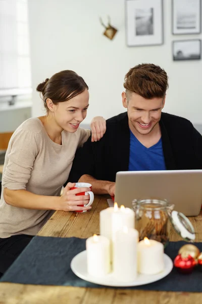 在圣诞节的时候看着笔记本电脑对年轻的夫妇 — 图库照片