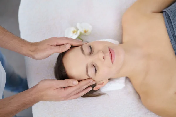 Молода жінка насолоджується масажем голови в центрі краси — стокове фото