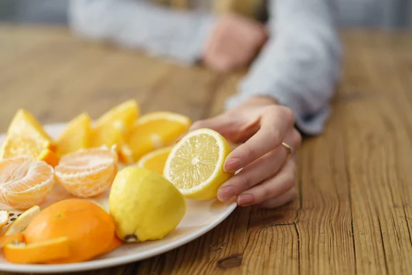 Γυναίκα βάζοντας φρέσκο λεμόνι και πορτοκάλι στο πιάτο — Φωτογραφία Αρχείου