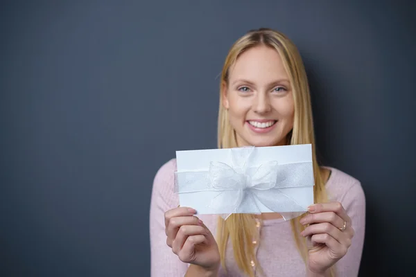 Mulher bonita segurando presente branco contra cinza escuro — Fotografia de Stock