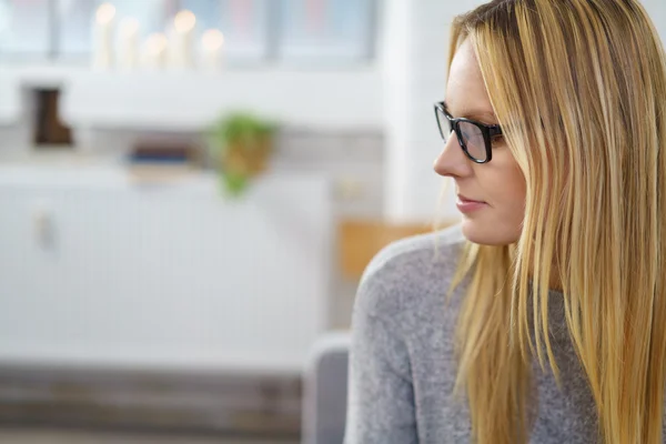 Hübsche blonde Frau sitzt und schaut aufmerksam zu — Stockfoto