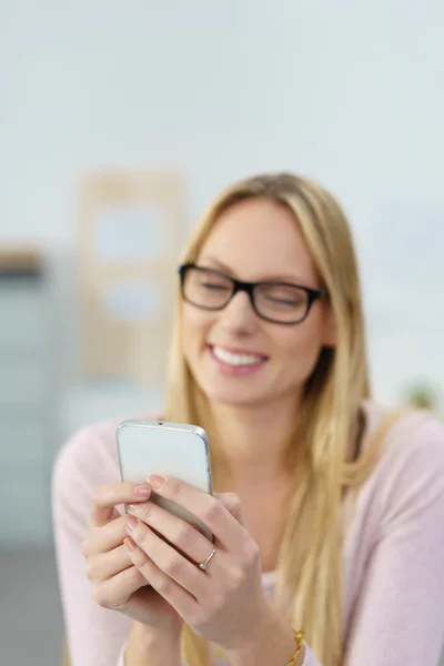 Lächelnde Frau liest SMS auf ihrem Handy — Stockfoto