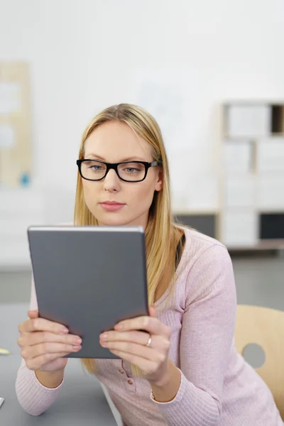 Young blonde woman reading on her tablet — Stockfoto