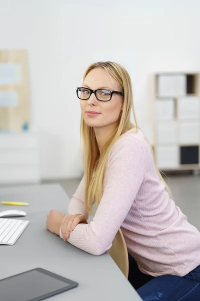 Junge Frau sitzt am Schreibtisch im Büro — Stockfoto