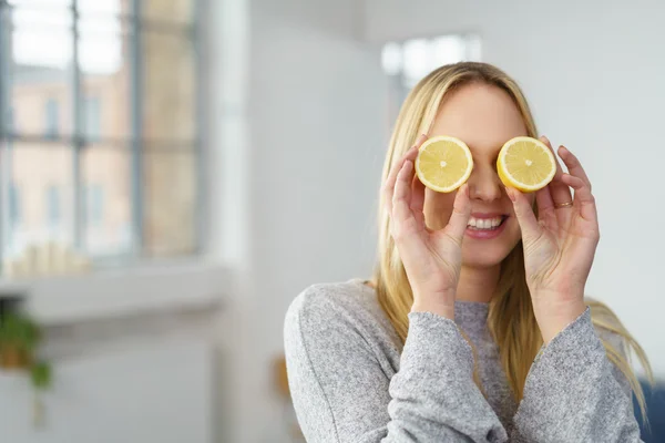 Woman holding lemons to her eyes — Stockfoto