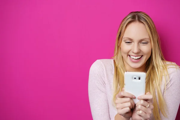 Happy woman looking at her mobile phone with a surprised smile — Stockfoto