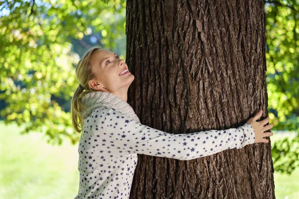 Bella donna abbracciare un enorme albero tronco — Foto Stock