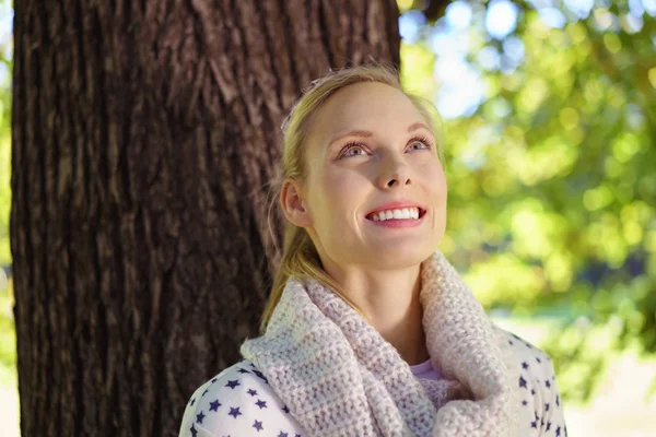 Mujer reflexiva feliz mirando hacia arriba contra el árbol grande —  Fotos de Stock