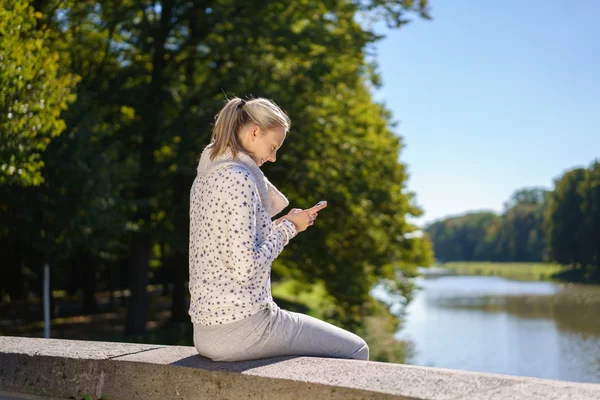 Aktivní mladá žena čte sms venku — Stock fotografie