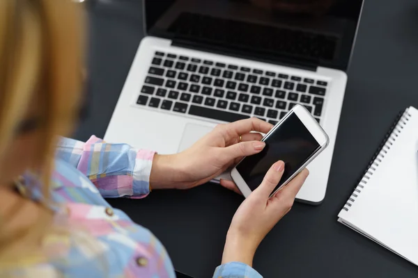 Mujer en el lugar de trabajo usando portátil y teléfono móvil —  Fotos de Stock