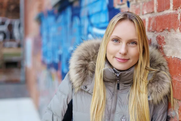 Moderne Frau lehnt an einer Ziegelmauer — Stockfoto