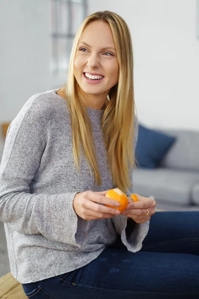 Lächelnde glückliche Frau beim Schälen einer Orange — Stockfoto