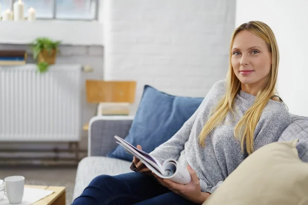 Frau entspannt sich auf ihrem Sofa und liest ein Tagebuch — Stockfoto