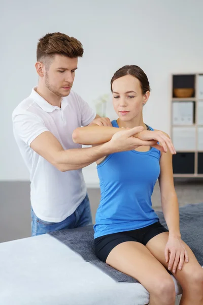 Fisioterapista che esamina la spalla ferita di una paziente all'interno della clinica . — Foto Stock