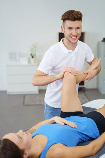 Fisioterapeuta examinando la rodilla lesionada de una paciente dentro de la clínica . — Foto de Stock