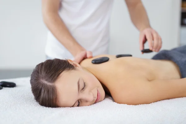 Jonge vrouw met een hot stone-massage — Stockfoto