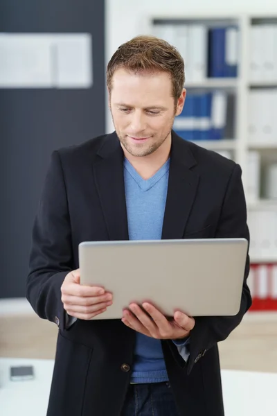 Zakenman staande lezing op zijn laptop — Stockfoto