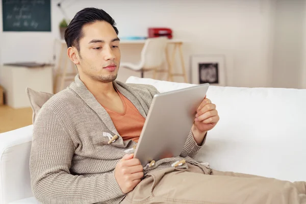 Молодой человек читает электронную книгу на планшете — стоковое фото