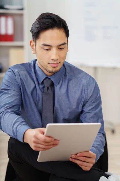 Junger asiatischer Geschäftsmann liest Daten auf einem Tablet — Stockfoto