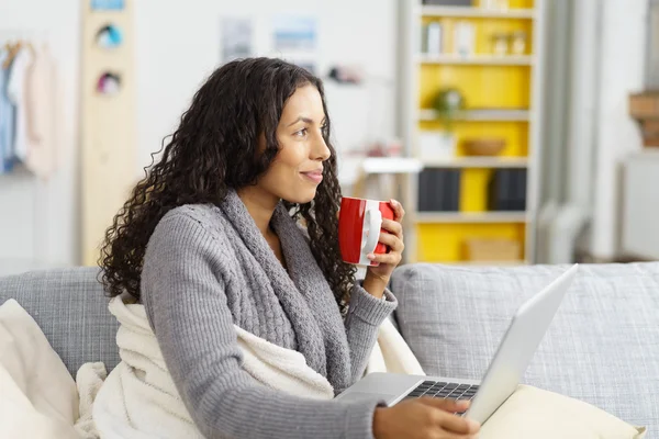 Cozy Young Woman with Mug and Laptop at Home — стокове фото