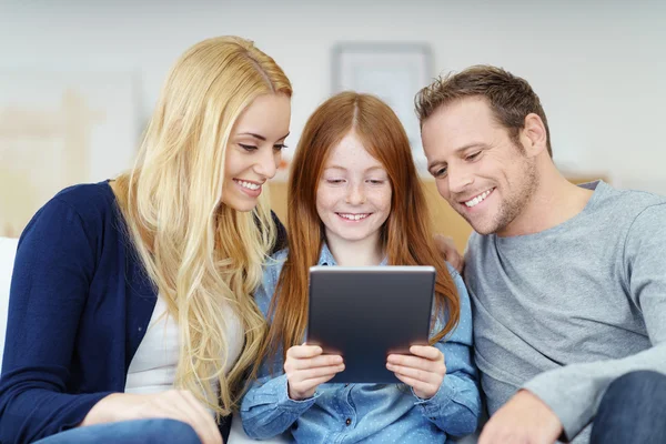 Família feliz compartilhando um computador tablet — Fotografia de Stock