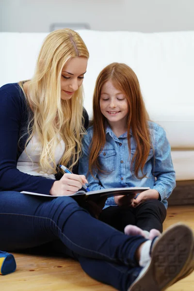 Giovane madre e figlia a fare i compiti insieme — Foto Stock