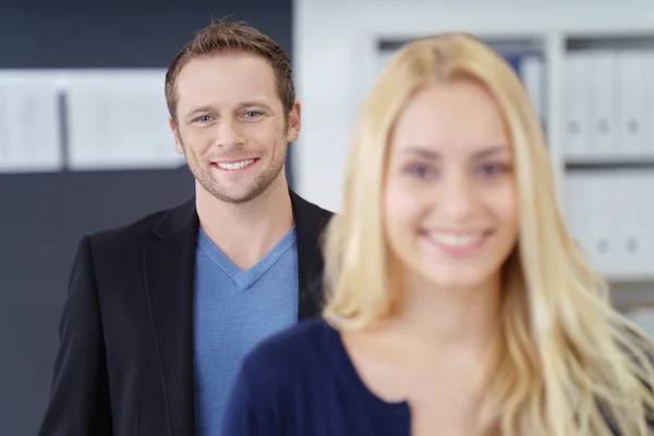 Grinning business man in office with woman — Stock Photo, Image