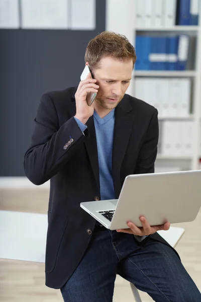 Executivo ocupado segurando laptop e telefone — Fotografia de Stock