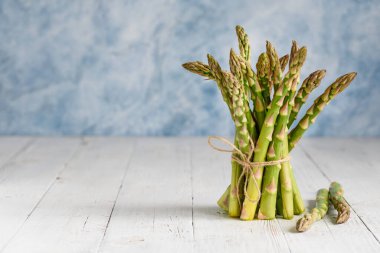 Tahta beyaz bir masada taze yeşil kuşkonmaz. Vejetaryen sağlıklı yiyecekler. Uzayı kopyala Seçici odak. 