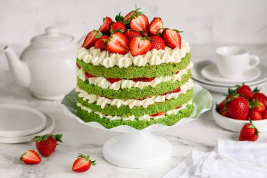 Kürsüde çilekli ve kremalı yeşil ıspanaklı kek. Doğum günü pastası. Seçici odak 