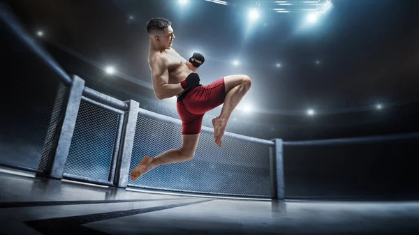 Klatka MMA. Skoki kolanem w ośmiokącie. Samiec skacze z kopnięciem kolana. Sport — Zdjęcie stockowe