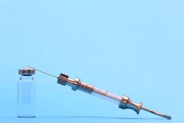 Mavi arka planda metal, cam ve şişeden yapılmış antika şırınga. Metin için boş alan. kopyalama alanı