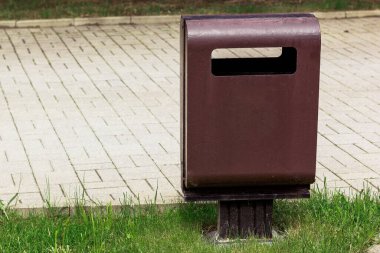 Pistin yanındaki parkta yalnız metal çöp tenekesi.