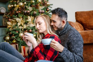 Mutlu çift Noel 'de ve yılbaşı partisinde sarılıp kahve, süt ya da çikolata içiyor. Hygge, boş zaman ve insanlar, mutlu yıllar konsepti.