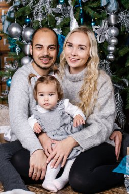 Noel için dekore edilmiş odada bebekli mutlu ebeveynler. Kış tatili Xmas ve Yeni Yıl konsepti