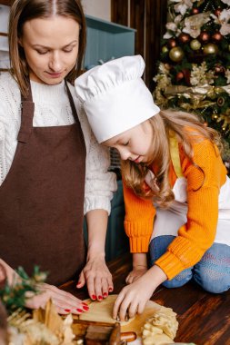 Evde şenlikli yemekler için aile hazırlığınız kutlu olsun. Anne ve kızı Noel kurabiyeleri hazırlıyorlar. Mutlu Noeller ve mutlu tatiller!