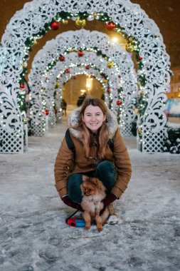 Köpeği Pomerian 'lı, açık havada, karın altında çok tatlı bir kız resmi. Kış zamanı