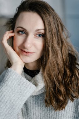 Güzel gülümseyen genç bir kadının yakın plan portresi. Gülümseyen hoş bir genç kadın evde geleceği hayal ediyor.